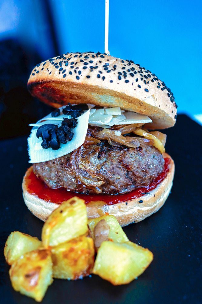 Un plato de ensalda con un gran bloque de queso tierno en el centro aliñado con vinagre de Módena.